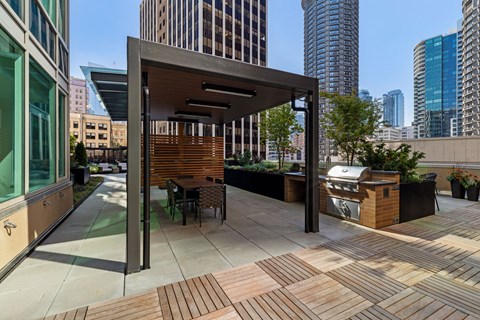 a rooftop patio with a grill and a dining area with a city in the background