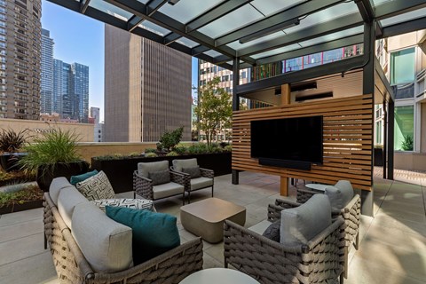 a terrace with a couch and chairs and a television