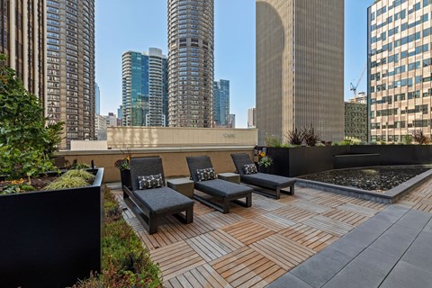 a rooftop deck with lounge chairs and a fountain and skyscrapers in the background