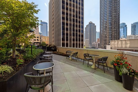 a rooftop patio with tables and chairs and a view of the city