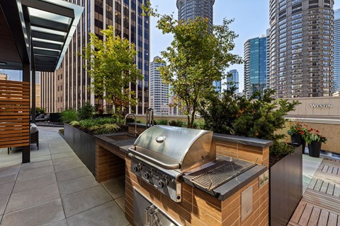 a barbecue grill on a patio with skyscrapers in the background