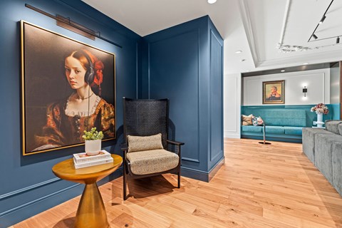 a living room with a large painting and a chair and a table