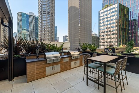 a rooftop patio with a grill and a table and chairs