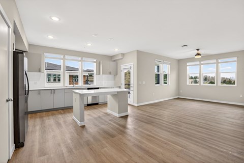 A kitchen with a refrigerator, table and cabinets.