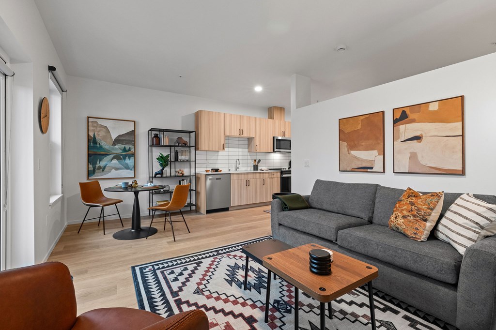 A living room with a grey couch, a coffee table, and a dining table with chairs.