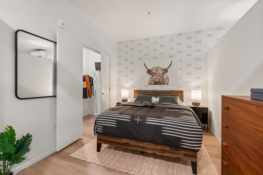 A bedroom with a bed, dresser, and mirror.