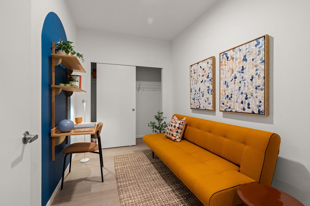 A yellow sofa sits in a room with two paintings on the wall.