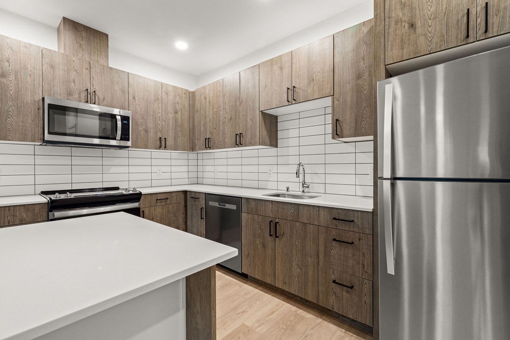 A modern kitchen with a stainless steel refrigerator and wooden cabinets.