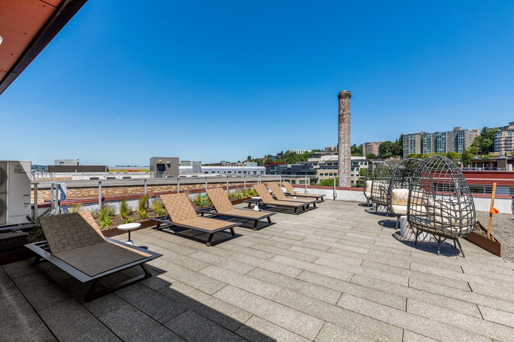 A rooftop patio with several lounge chairs and a table.