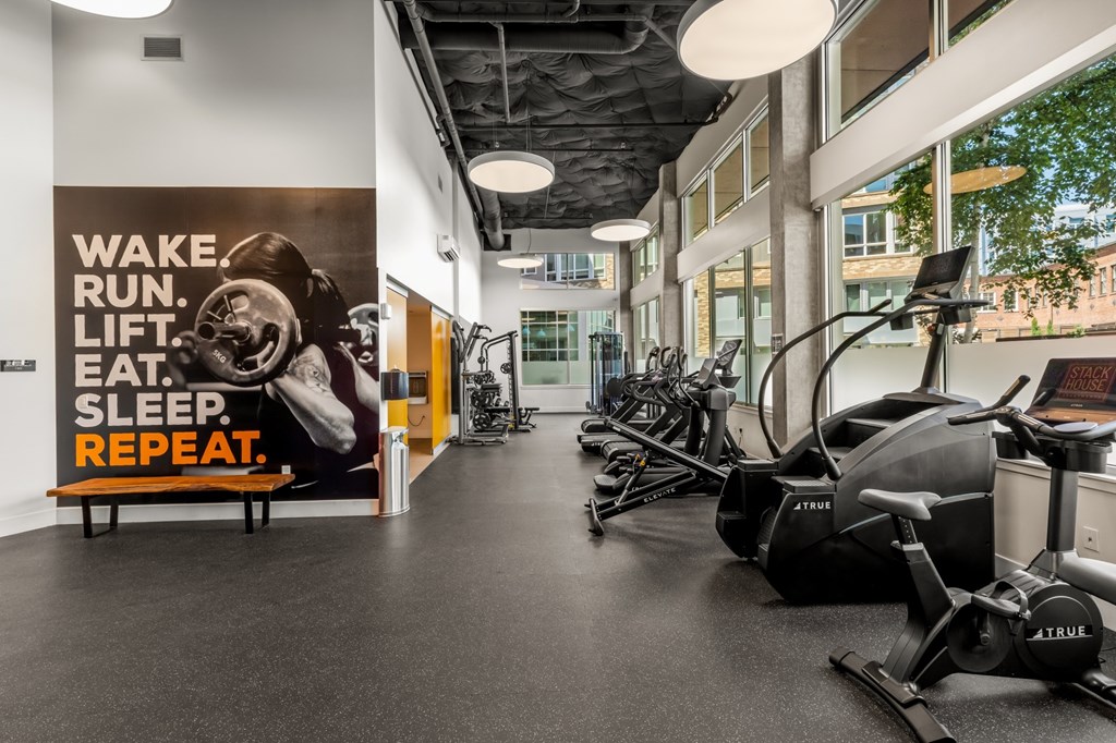 A gym with a poster on the wall that says "WAKE. RUN. LIFT. EAT. SLEEP. REPEAT."