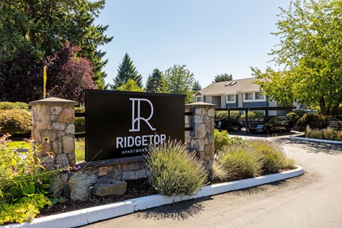 A sign for Ridgetop Apartments is displayed in front of a building.