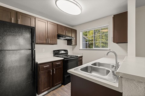 A kitchen with brown cabinets and a black refrigerator.