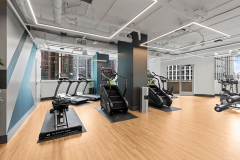 a gym with treadmills and other exercise equipment on a wood floor