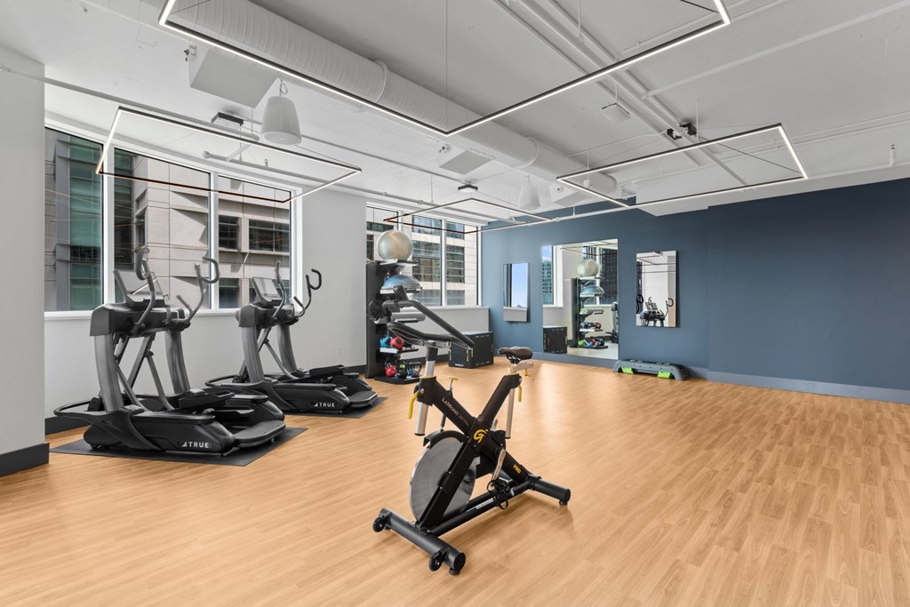 a gym with treadmills and other exercise equipment on a wooden floor