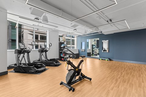 a gym with treadmills and other exercise equipment on a wooden floor