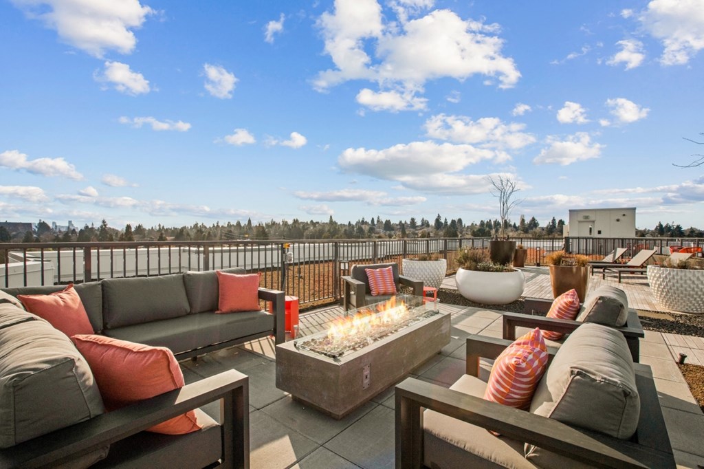 a rooftop patio with couches and a fire pit