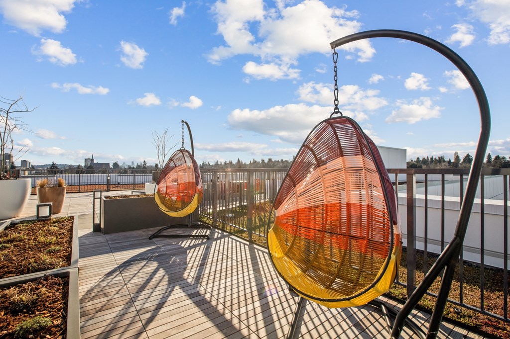 a pair of orange and yellow hammock chairs on a roof top patio