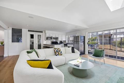 A modern living room with a white couch and a glass table.