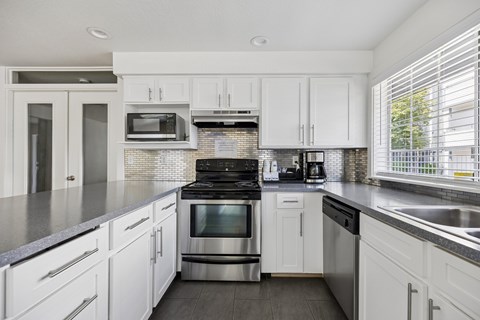 A modern kitchen with white cabinets and stainless steel appliances.