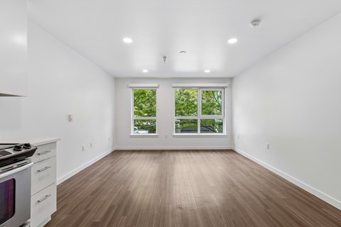 A white room with a wood floor and a window with a view of trees.