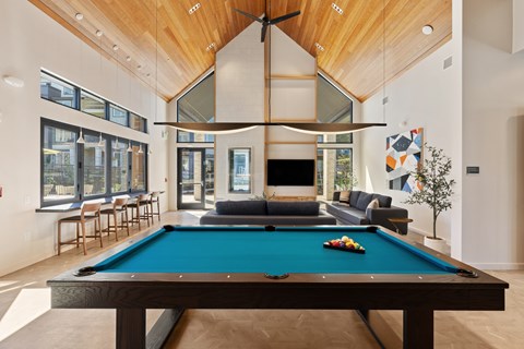 A pool table in the middle of a room with a high ceiling and a fireplace.