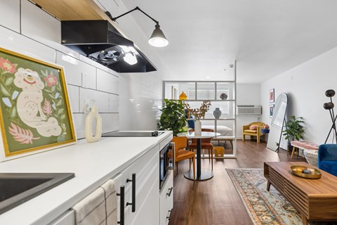 A kitchen with a white counter top and wooden floors.