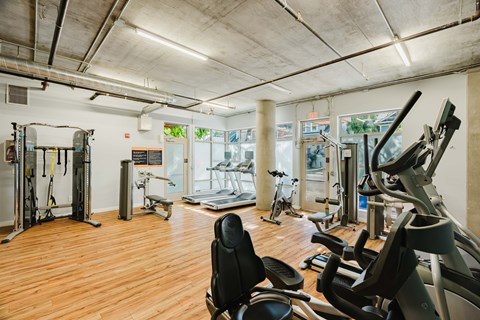 A gym with a variety of equipment including treadmills, weights, and exercise machines.