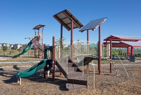 A playground with a green slide and a red and white striped slide.