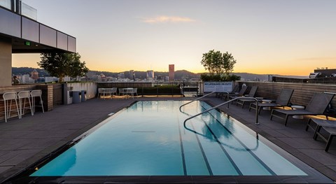 A swimming pool on a rooftop with a sunset in the background.