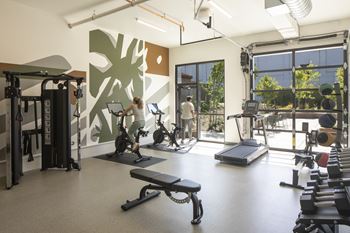 A woman is working out on a treadmill in a gym with a green leaf pattern on the wall.