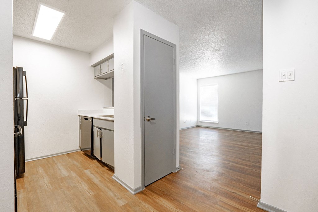 an empty kitchen and living room with wood flooring and a refrigerator