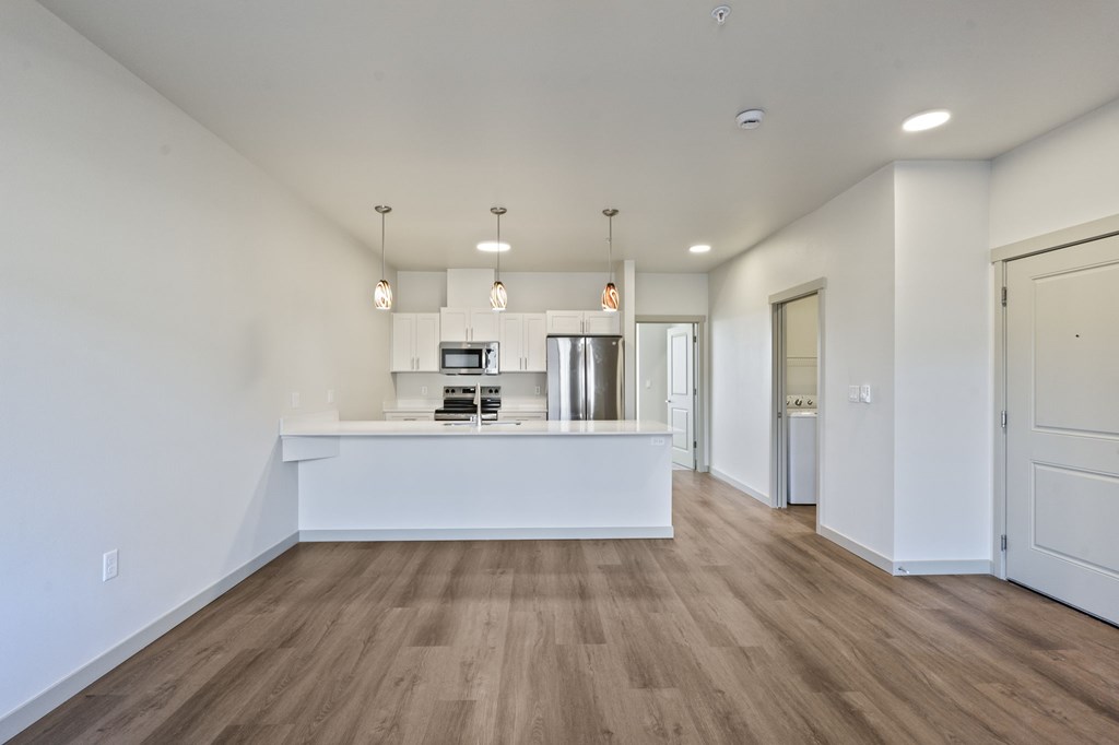 A spacious room with a long white counter and wooden flooring.