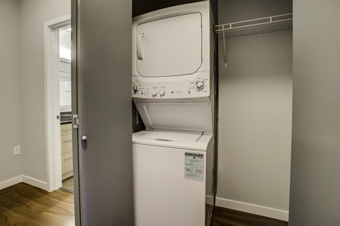 A white dishwasher is in a narrow space between a wall and a door.