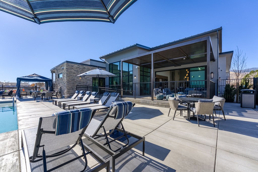 a patio with chairs and tables and a building with a pool