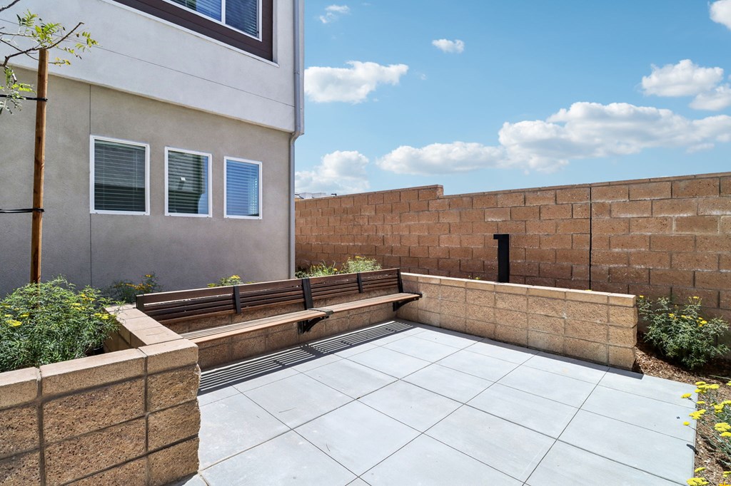 A modern house with a grey tiled patio and a brick wall.