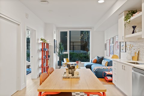 A modern kitchen with a wooden table and orange chairs.