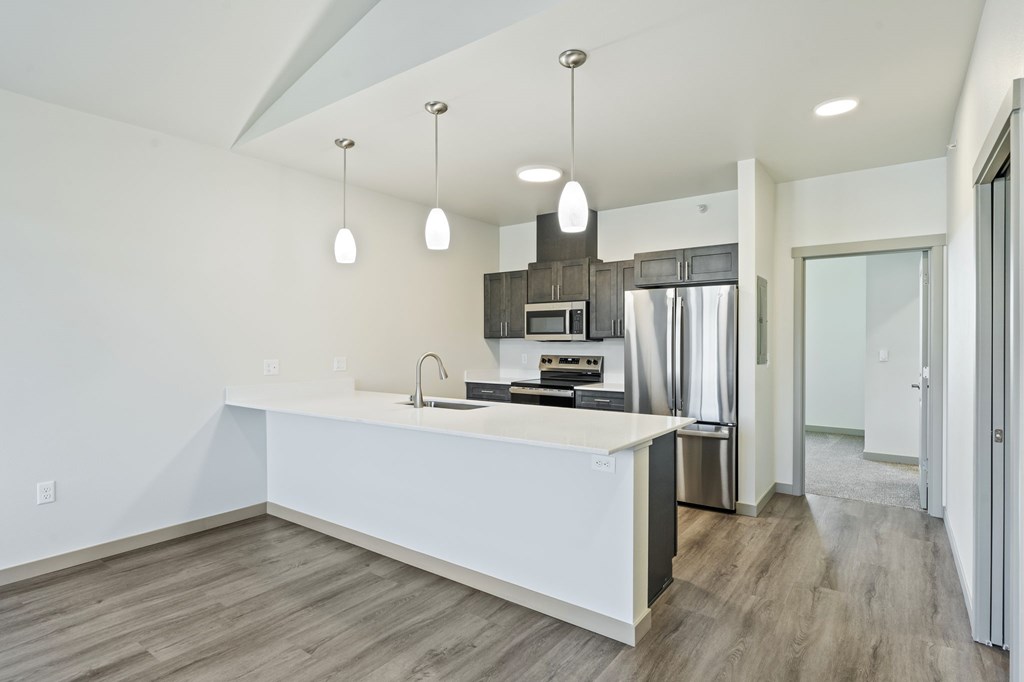 A modern kitchen with a white countertop and wooden flooring.