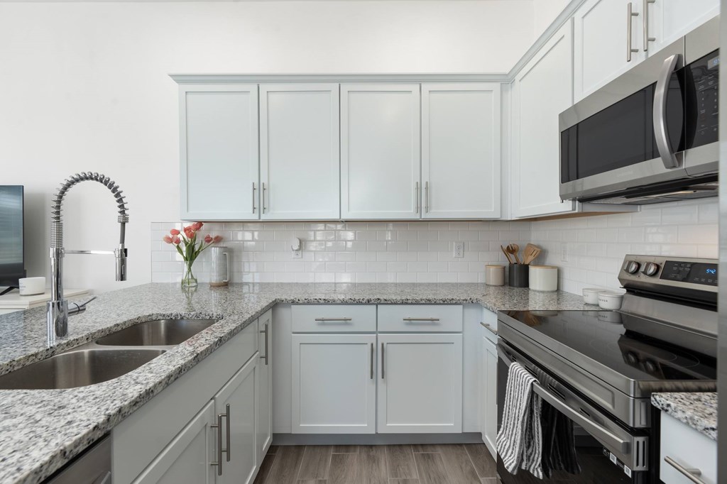 A kitchen with white cabinets and a black microwave.