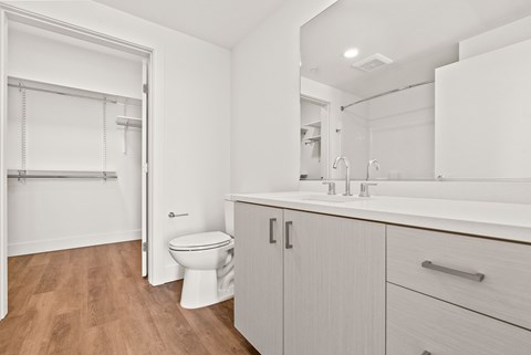 A white bathroom with a toilet, sink, and wooden floors.