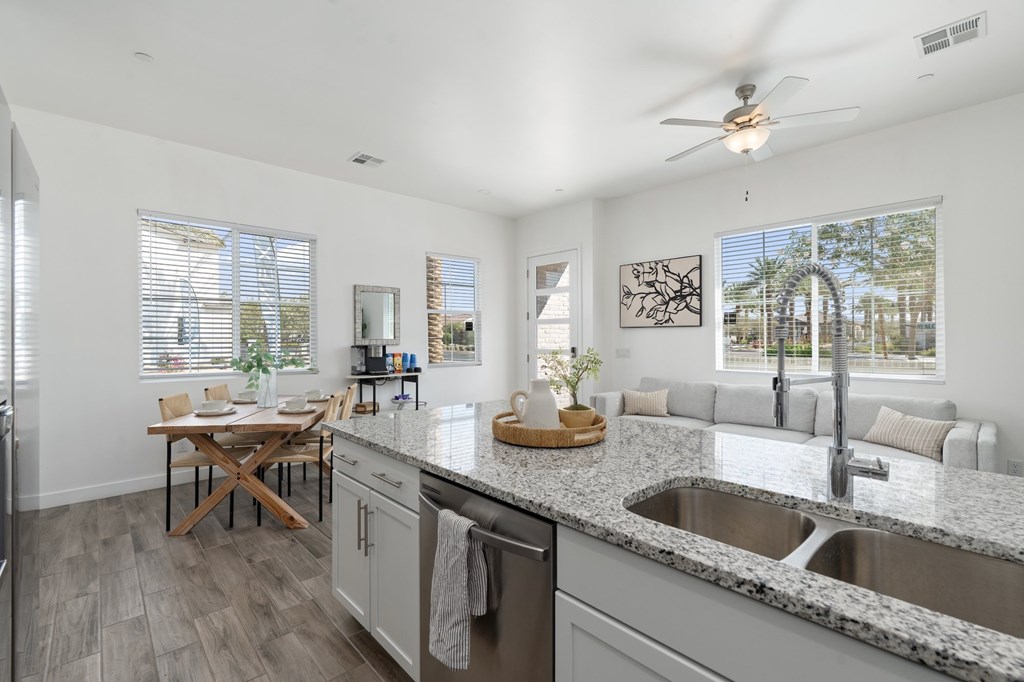 A modern kitchen with a dining table and a ceiling fan.