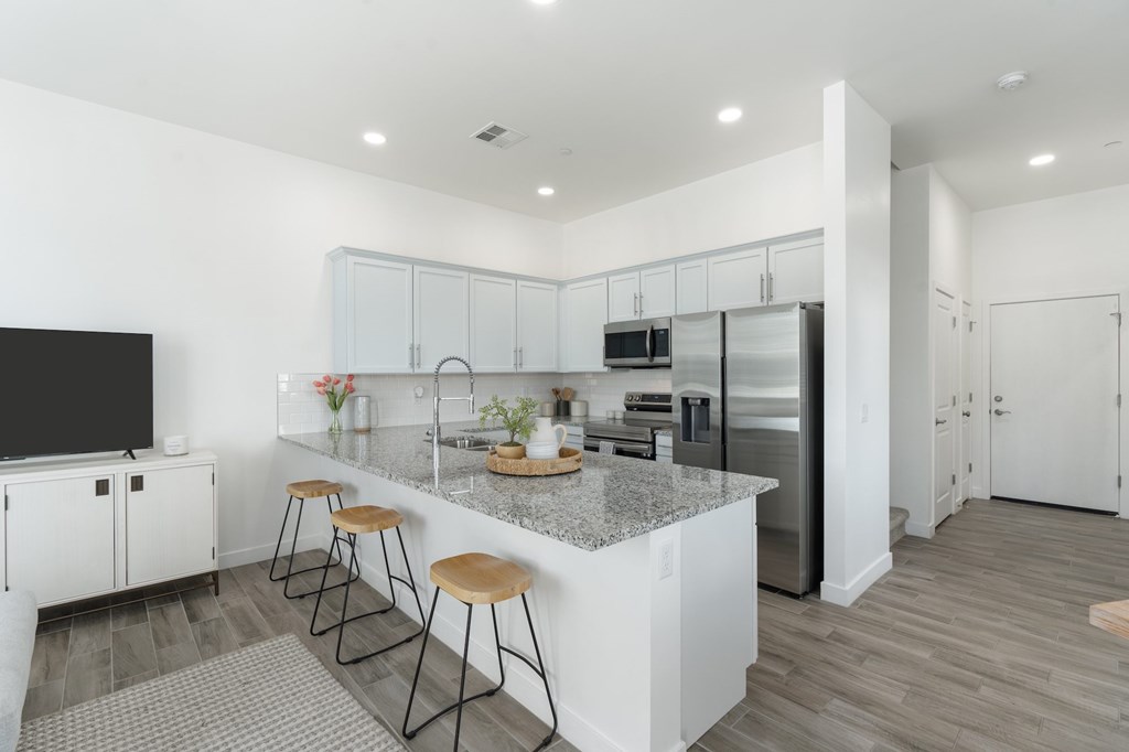 A kitchen with white cabinets and a granite countertop.