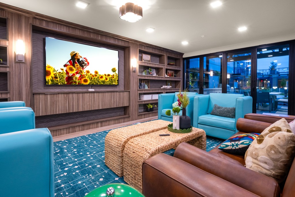 A living room with a large screen television and comfortable seating.
