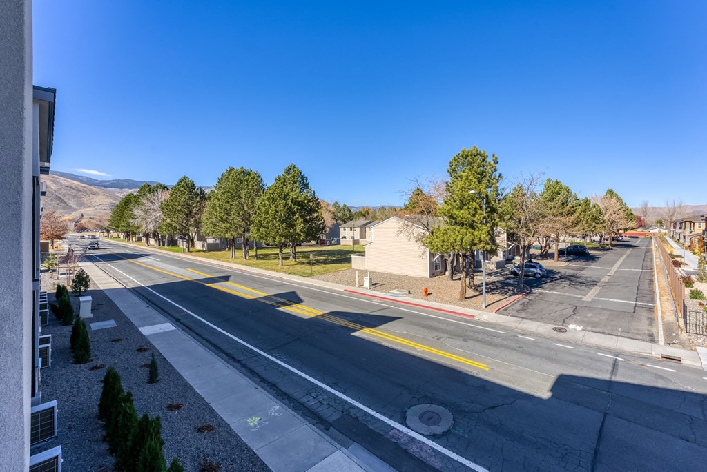 an empty street with trees and buildings on the side of the road