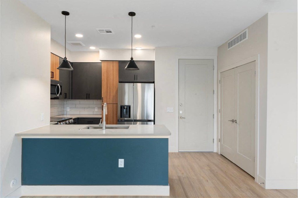 a renovated kitchen with a blue island and a stainless steel refrigerator