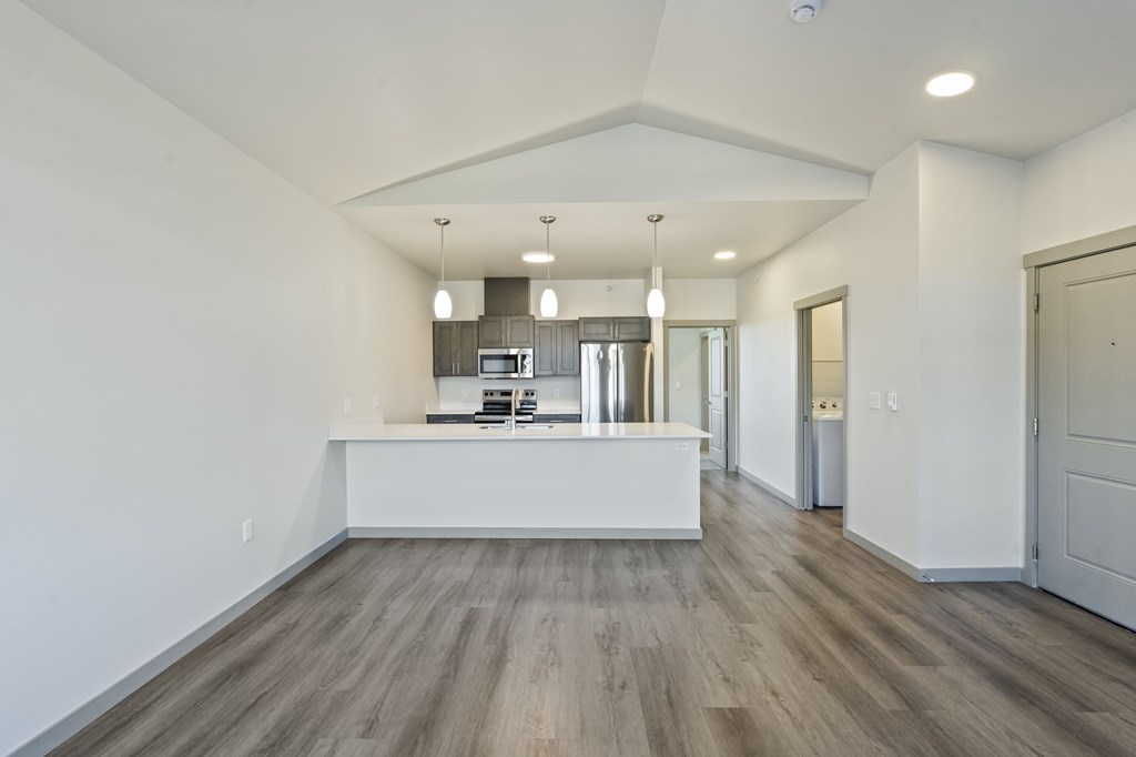 A spacious kitchen with a white countertop and wooden flooring.
