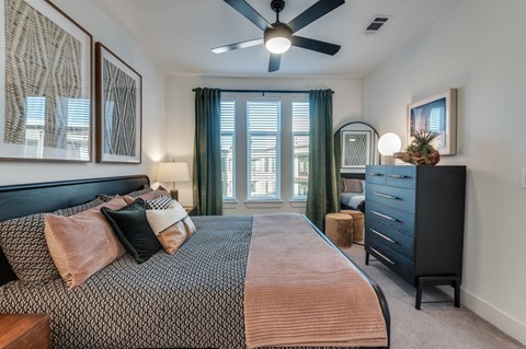 A bedroom with a large bed and a ceiling fan.