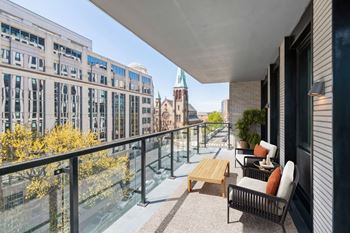A balcony with a table and chairs overlooks a city street.