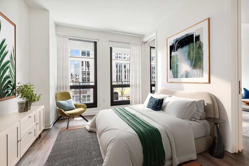 A bedroom with a large bed and a chair.