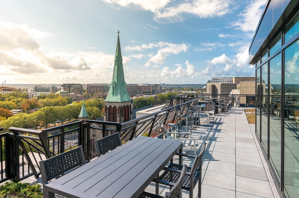 A view of a city from a rooftop with a green spire in the distance.