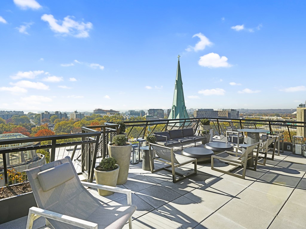 A patio with chairs and a table overlooking a cityscape.